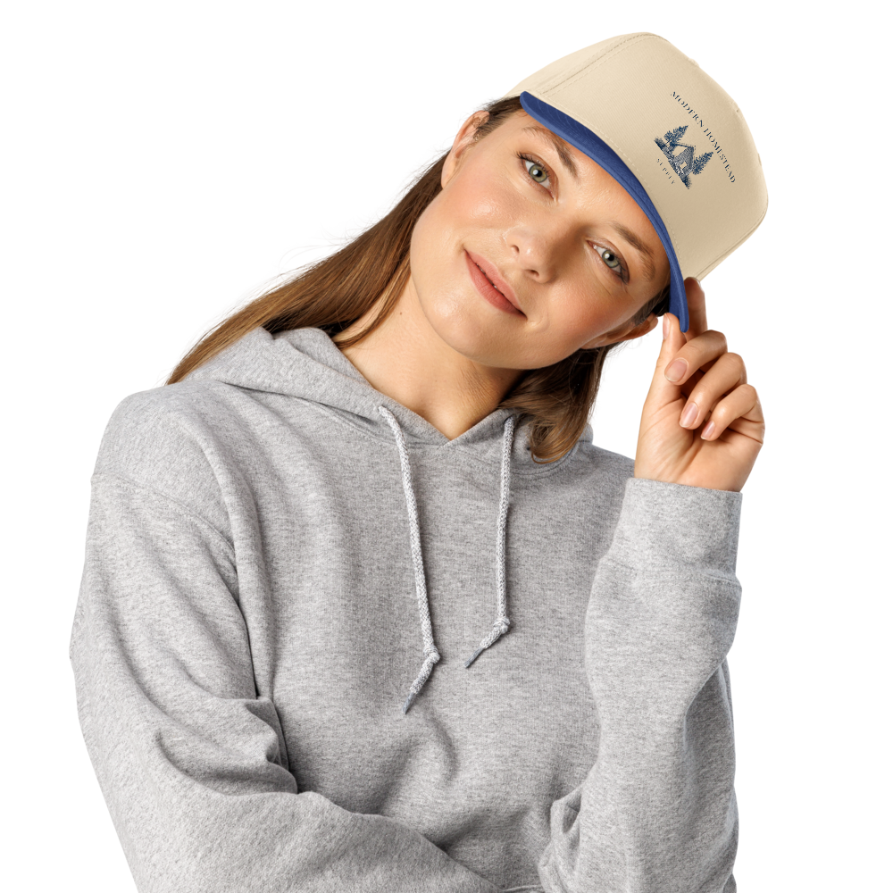 Person wearing a gray hoodie and beige cap with blue band, on a white background