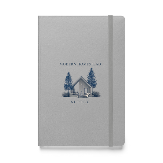 Gray notebook with a cabin and tree illustration on the cover, labeled 'Modern Homestead Supply'.