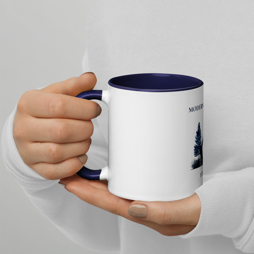 Hand holding a white mug with a blue interior and design on a light gray background